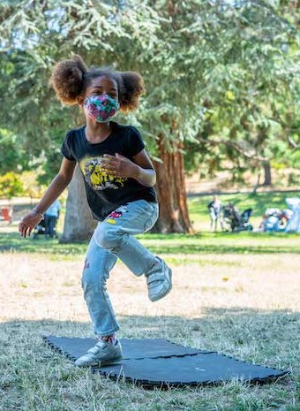 Camp Destiny - Destiny Arts Youth Dancing with afro puffs hair style wearing a mask and dancing outdoors in the park on a sunny day